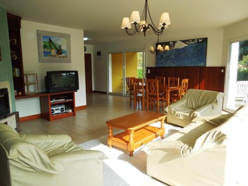 un salon avec des canapés, une table et une télévision dans l'établissement Arbousiers - Seignosse agréable villa contemporaine, à Seignosse