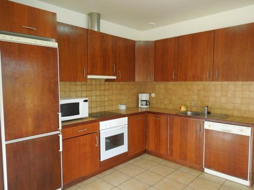 - une cuisine avec des placards en bois et des appareils blancs dans l'établissement Arbousiers - Seignosse agréable villa contemporaine, à Seignosse