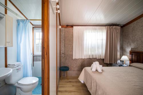 a bedroom with a bed and a toilet and a sink at Camping Baltar in Portonovo