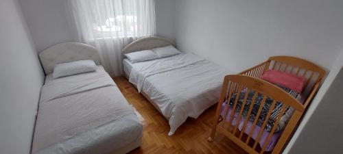 プルジネにあるApartman Bujišićのベビーベッド付きの小さな部屋のベッド2台