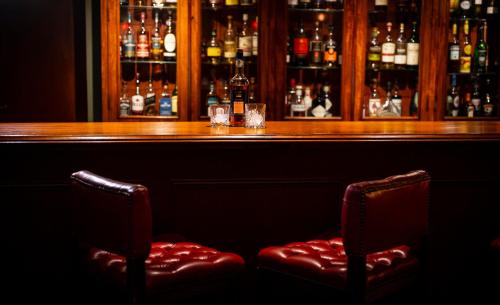 a bar with two red chairs in front of a bar at Knipoch House Hotel in Oban