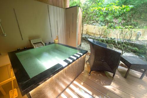 a swimming pool on a deck with two chairs at Ryokan Sumiya Kihoan in Kameoka