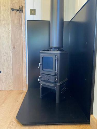 a kitchen with a stove with a tv in it at The Black Swan Shepherd Hut in Ketton