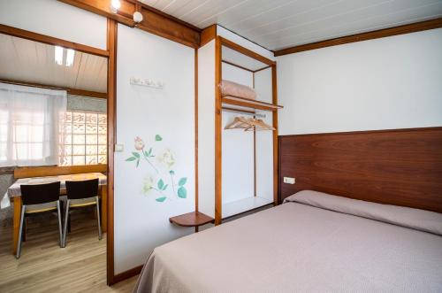 a bedroom with a bed and a table and a dining room at Camping Baltar in Portonovo
