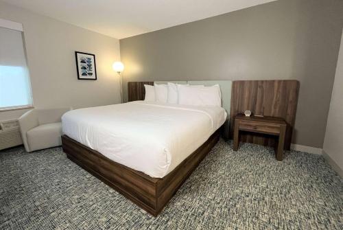 a bedroom with a large bed with white sheets and pillows at Wingate by Wyndham Hattiesburg in Hattiesburg