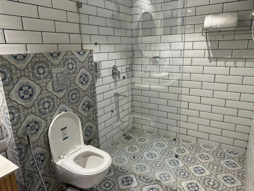a bathroom with a toilet and a tiled wall at Kaffberry Cafe & Homestays in Kūd