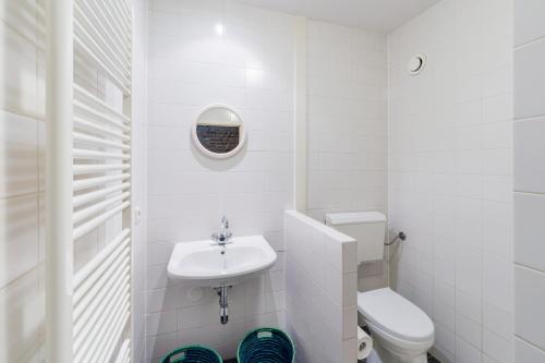 a white bathroom with a toilet and a sink at Meschermolen 12 in Eijsden