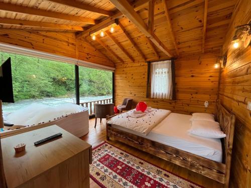 1 dormitorio con 1 cama en una cabaña de madera en Teona Bungalow & Restaurant, en Çiğil