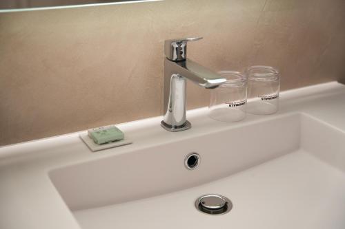 a sink with a faucet and two glasses on it at Hôtel du Golf de l'Ailette, The Originals Relais in Chamouille