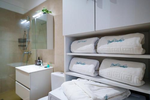 a bathroom with a pile of towels on a shelf at Royale Sundance 224 Infinity Beach Pool & Spa Mamaia Nord in Mamaia Nord