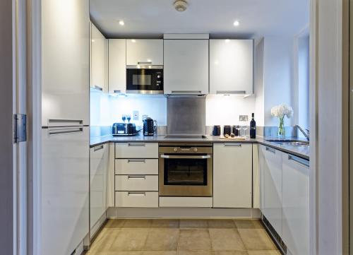 a white kitchen with white cabinets and appliances at Oxford Street Fitzrovia Apartments by D'Montrio in London
