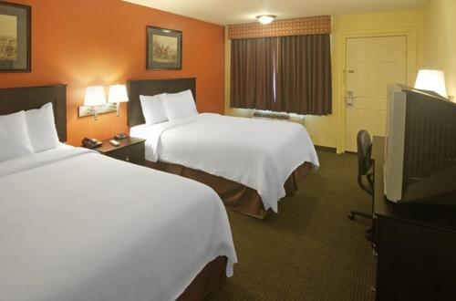 a hotel room with two beds and a flat screen tv at Americas Best Value Inn Waco - Franklin Avenue in Waco