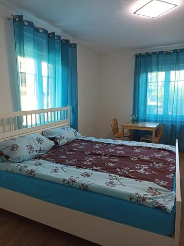 1 dormitorio con 1 cama con cortinas azules y mesa en Zimmer "Türkis", en Lahr-Dinglingen