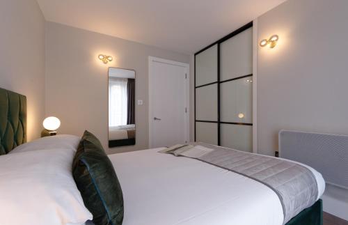a bedroom with a large white bed and a mirror at Oxford Street Fitzrovia Apartments by D'Montrio in London
