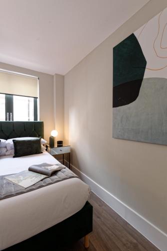 a bedroom with a bed and a painting on the wall at Oxford Street Fitzrovia Apartments by D'Montrio in London