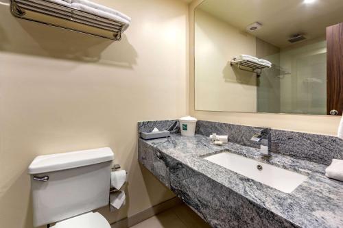 een badkamer met een wastafel, een toilet en een spiegel bij Quality Inn Chihuahua San Francisco in Chihuahua