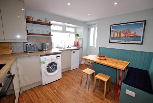 a kitchen with a washing machine and a table at Auld Fishers Catch- homely apartment near the sea in Anstruther