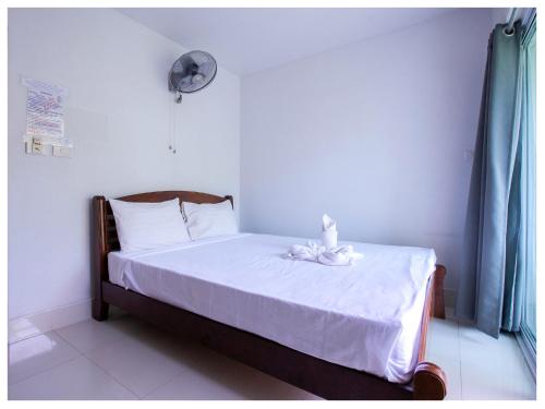 a bedroom with a bed with white sheets and a fan at Namhasin House in Koh Tao