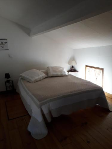 a bedroom with a bed in a white room at La P'tite Maison in Lisle