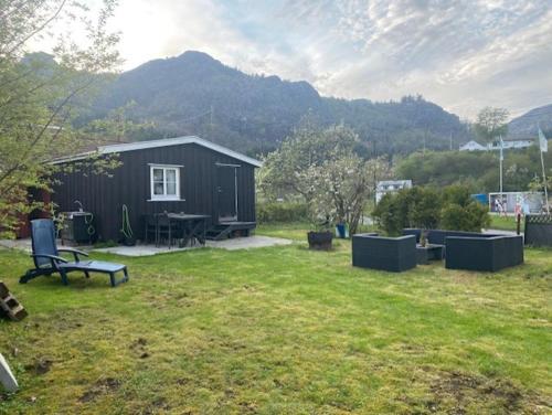 ein schwarzer Schuppen mit einem Tisch und einer Bank in einem Hof in der Unterkunft Løkka,Summer cabin! in Åna-Sira