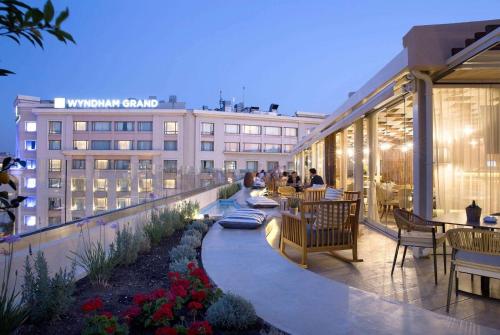 eine Dachterrasse mit Tischen und Stühlen und ein Gebäude in der Unterkunft Wyndham Athens Residence in Athen