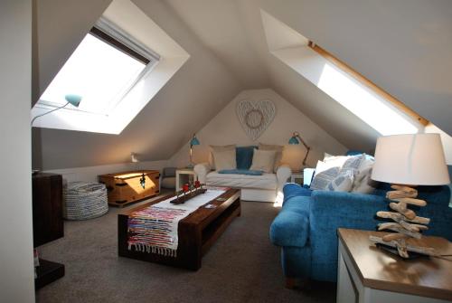 ein Wohnzimmer im Dachgeschoss mit einem blauen Sofa und einem Tisch in der Unterkunft Turnstone- beautiful coastal home Pittenweem in Pittenweem