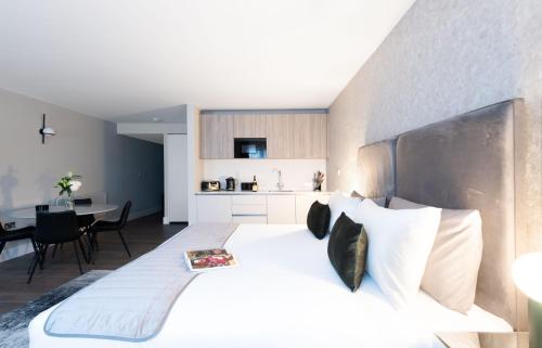 a bedroom with a large white bed and a kitchen at Oxford Street Fitzrovia Apartments by D'Montrio in London
