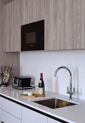 a kitchen with a sink and a bottle of wine at Oxford Street Fitzrovia Apartments by D'Montrio in London