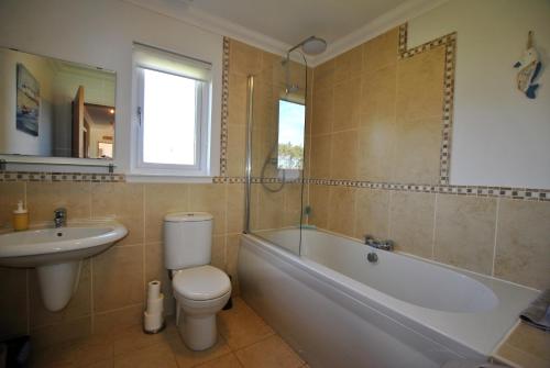 a bathroom with a toilet and a tub and a sink at Kellie View near Anstruther in Carnbee