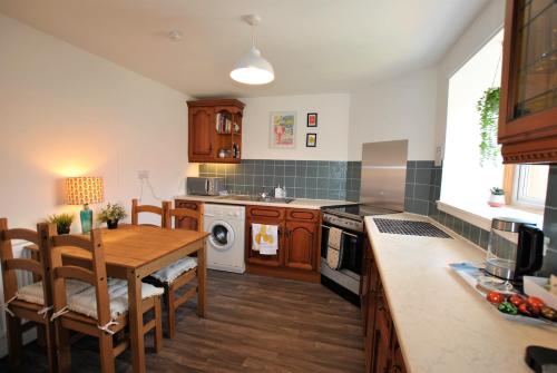 a kitchen with a wooden table and a dining room at Dookers Nook- Quirky coastal cottage Pittenweem in Pittenweem