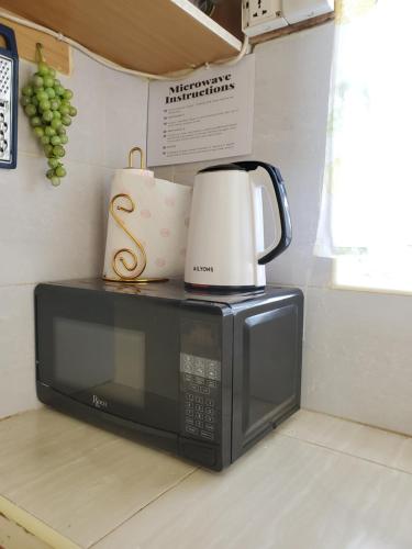 eine Mikrowelle mit Kaffeemaschine darüber in der Unterkunft 1 BR, TreasureTree Homes, Thika in Thika