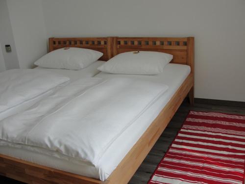 uma cama com uma estrutura de madeira e lençóis e almofadas brancos em Ferienwohnung Berliner Hof em Kiel