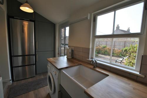 a kitchen with a sink and two windows at Woods Neuk-stunning character cottage East Neuk in Pittenweem