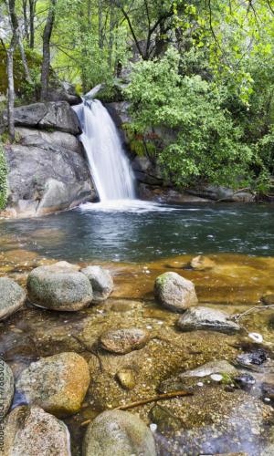a waterfall in the middle of a river with rocks at Casa Rural La Chistera in Avila