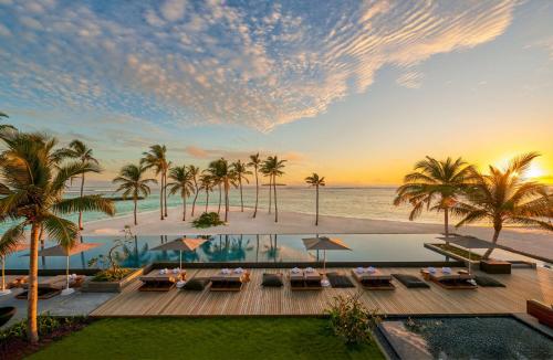 um resort com piscina, palmeiras e oceano em Alila Kothaifaru Maldives 