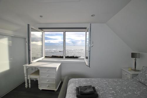 ein Schlafzimmer mit Bett, Schreibtisch und Fenster in der Unterkunft The Wendy House-seafront cottage incredible views in Anstruther
