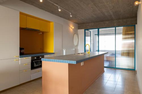 uma cozinha com armários amarelos e uma bancada em Spacious family flat near the beach (6-8 pers) em Koksijde
