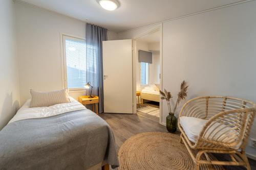 ein Schlafzimmer mit einem Bett, einem Stuhl und einem Spiegel in der Unterkunft Sun Villas A23 in Kalajoki