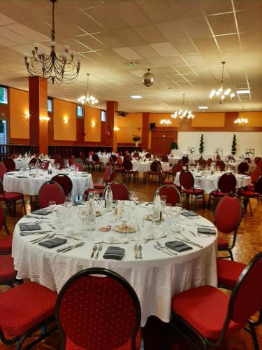 une salle à manger avec des tables blanches et des chaises rouges dans l'établissement Au Relais de l'Oust, à Josselin