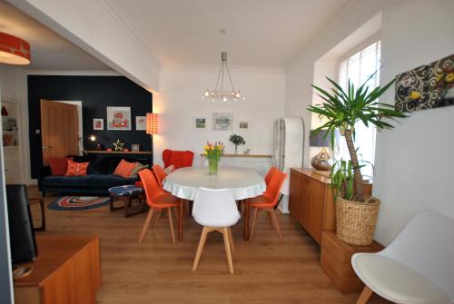 a living room with a white table and orange chairs at Shore Cottage Anstruther- stylish home by the sea in Anstruther