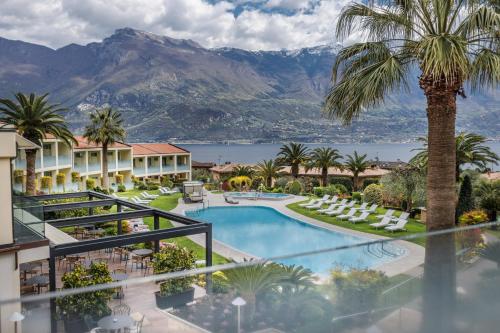 a resort with a pool and palm trees and mountains at Park Hotel Imperial in Limone sul Garda