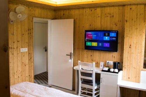 a room with a tv on a wooden wall at Kaffberry Cafe & Homestays in Kūd