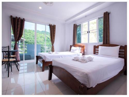 a bedroom with two beds and a table and windows at Namhasin House in Koh Tao