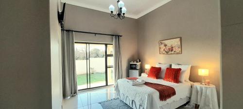 a bedroom with a bed with red pillows and a window at The Dream Guesthouse in Ermelo