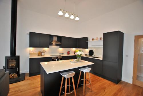 a kitchen with black cabinets and a stove at Academy Apartment Anstruther- stunning luxury home in Anstruther