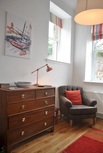 a bedroom with a dresser and a chair and a lamp at Academy Apartment Anstruther- stunning luxury home in Anstruther