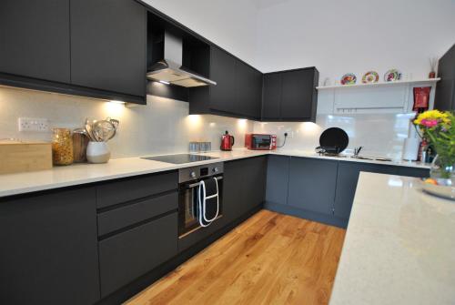 a kitchen with black cabinets and a wooden floor at Academy Apartment Anstruther- stunning luxury home in Anstruther