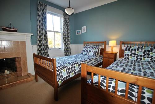 a bedroom with two beds and a fireplace at Willow Cottage- charming cottage in East Neuk in Pittenweem