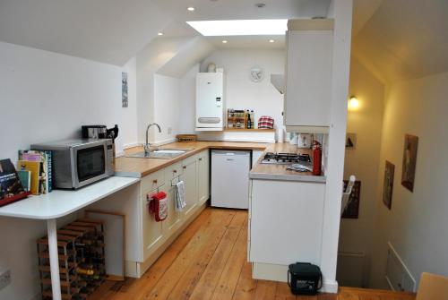 een keuken met witte kasten, een wastafel en een magnetron bij The Loft- charming character cottage in East Neuk in Anstruther