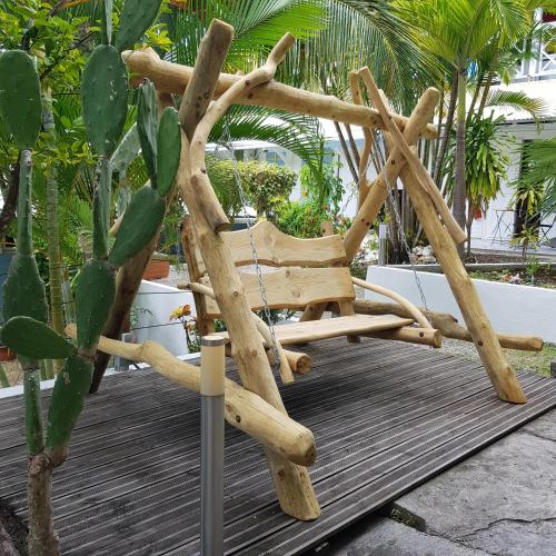 a wooden chair sitting on a deck next to a cactus at La plage de Petit-Havre in Le Gosier
